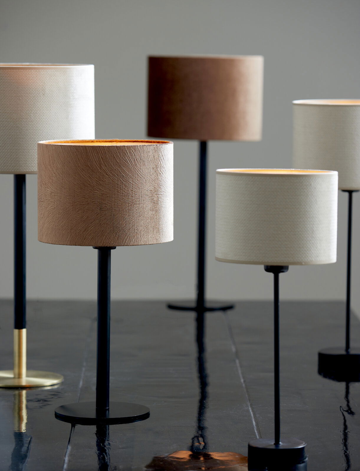 Mehrere moderne Lampenfüße mit verschiedenen Schirmfarben auf einem Tisch, seitliche Perspektive