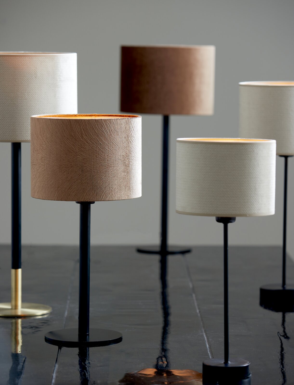 Meerdere moderne lampvoeten met lampenkappen in verschillende kleuren op een tafel, zijaanzicht