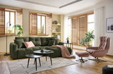 Gemütliche Wohnzimmer-Ecke mit einer grünen Rundecke, dekoriert mit Kissen und einer Decke, aus der Perspektive von vorne betrachtet.
