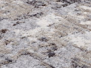 Nahaufnahme eines Designer Teppichs mit weicher, flauschiger Textur in Grau- und Beigetönen.