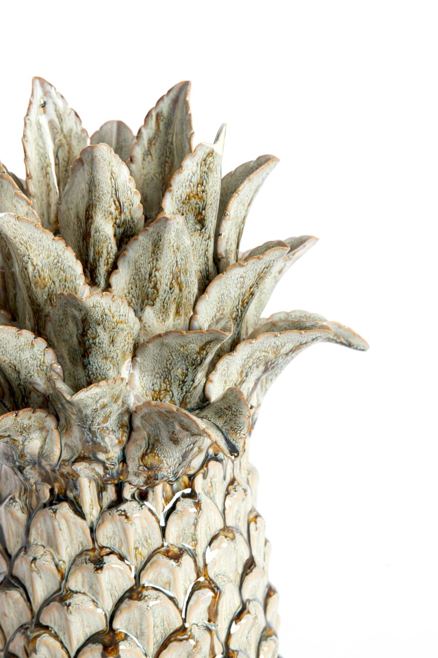 Nahaufnahme eines dekorativen Keramik-Ornaments in Form einer Ananas mit detaillierter Blattstruktur, seitliche Perspektive.