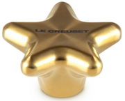 Goldener sternförmiger Deckelknopf von oben betrachtet, mit der Aufschrift 'LE CREUSET'.