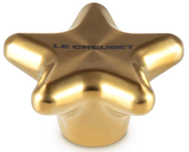 Goldener sternförmiger Deckelknopf von oben betrachtet, mit der Aufschrift 'LE CREUSET'.