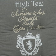 Niederlehnerauflage mit Schriftzug 'High Tea: Sandwiches, Sweets, Cake, Coffee & tea' und einem Wappen mit Löwenmotiv, Vorderansicht