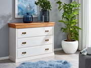 Weiße Kommode mit drei Schubladen und Holzplatte, dekoriert mit blauen Glasvasen, in einem modernen Wohnzimmer mit Pflanzen und Kunstwerk an der Wand, seitliche Perspektive.