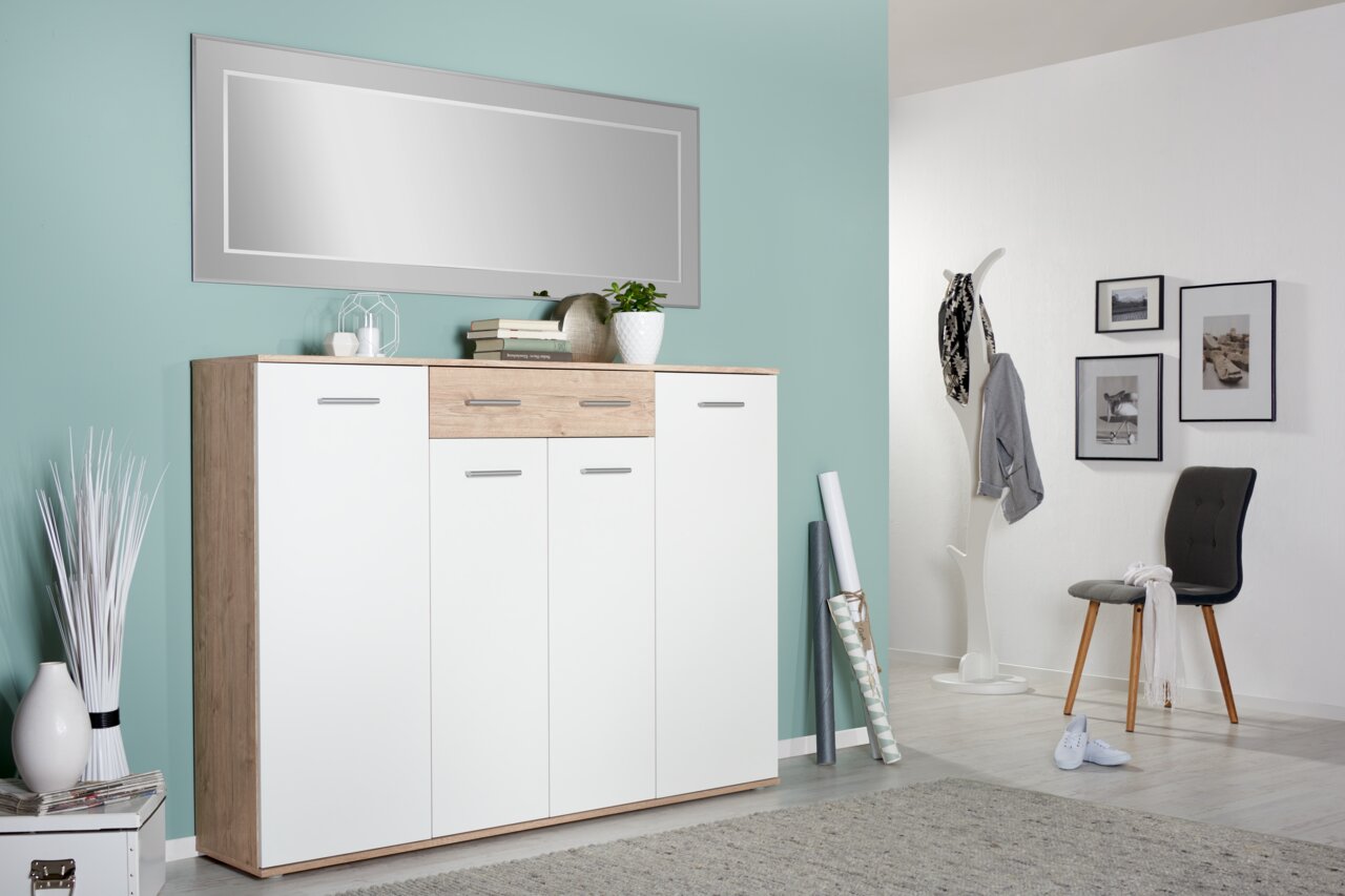 Moderner XL-Schuhschrank in Holzoptik mit weißen Türen, frontal fotografiert, in einem stilvoll eingerichteten Raum mit grüner Wand und Dekoration.