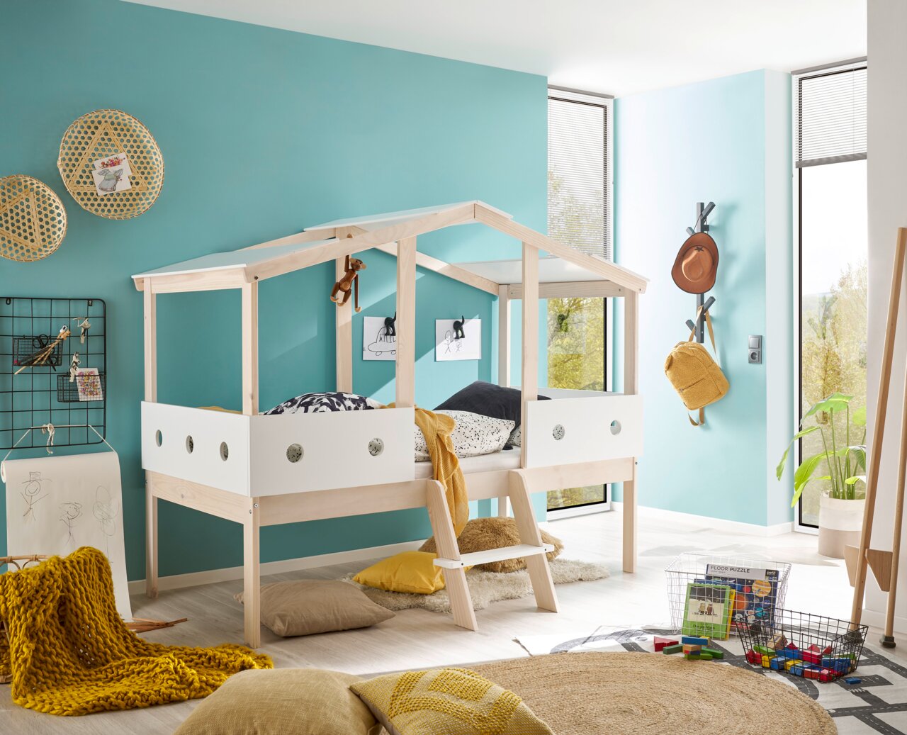 Spielbett in Hausform aus hellem Holz mit weißem Geländer, seitliche Perspektive