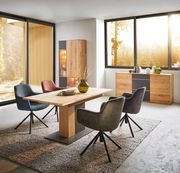 Modernes Esszimmer mit einem hölzernen Sideboard, zwei Türen, in einer hellen, von großen Fenstern umgebenen Umgebung, mit einem Esstisch und bunten Stühlen, seitliche Perspektive.