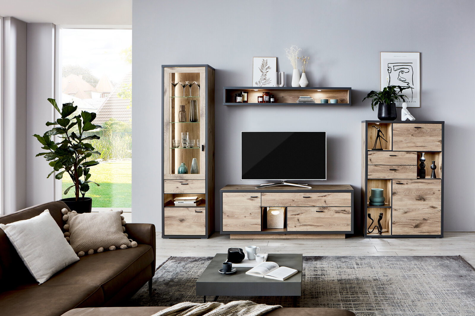 Moderne Wandkombination ORLANDO in Holzoptik mit TV-Schrank, Vitrine und Regalen, frontal fotografiert in einem stilvollen Wohnzimmer.