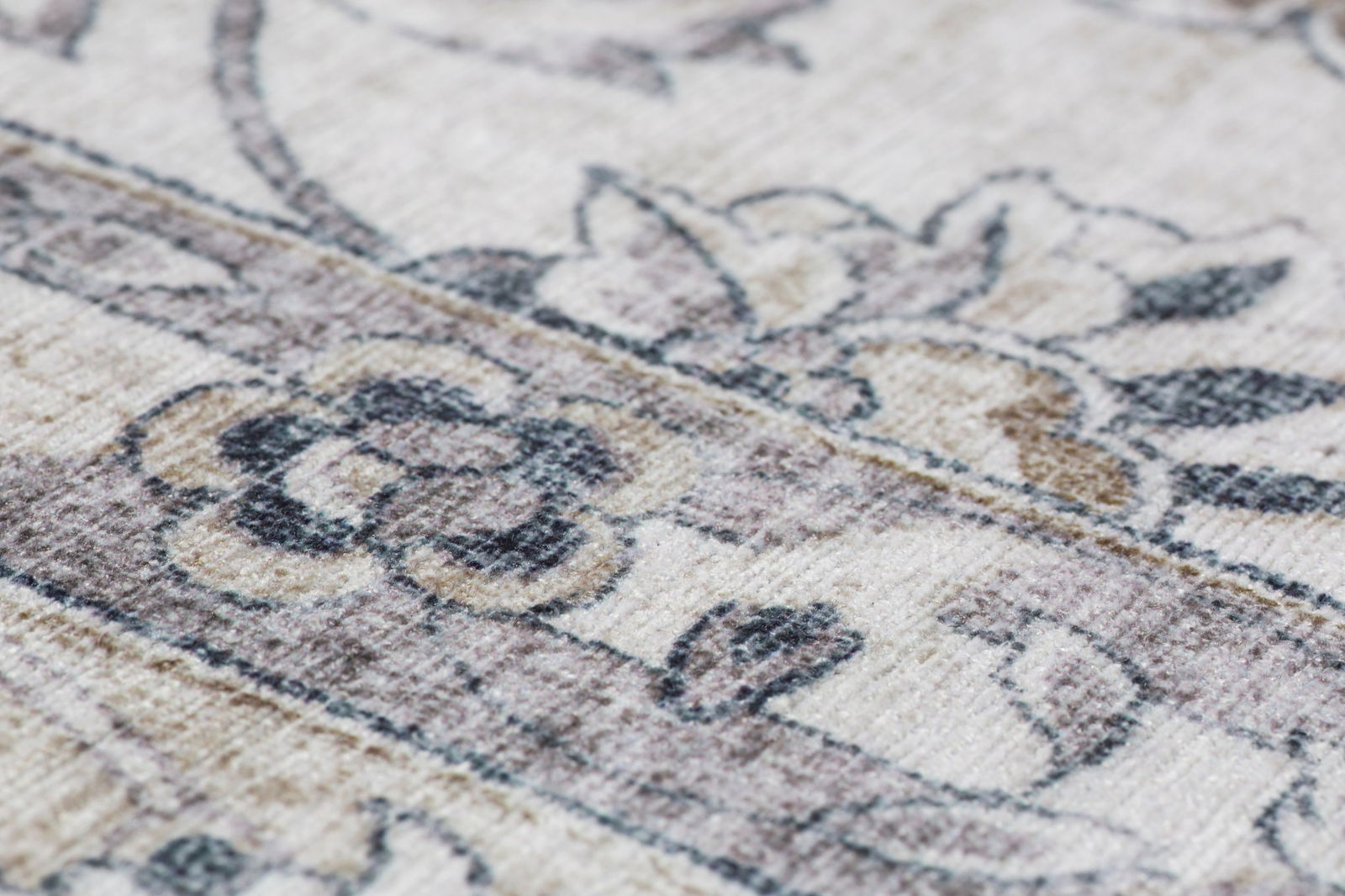 Nahaufnahme eines Teppichs mit floralen Mustern in Beige- und Grautönen, seitliche Perspektive