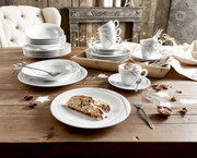 Ein stilvolles Kombiservice-Set mit 30 Teilen, präsentiert auf einem rustikalen Holztisch. Das Set umfasst Teller, Schalen und Tassen mit elegantem Design, ideal für festliche Anlässe. Perspektive: Draufsicht.