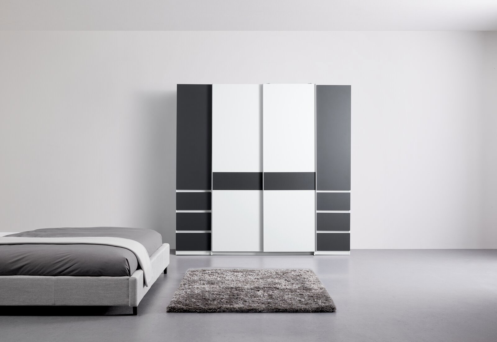 Moderner Dreh- und Schwebetürenschrank mit vier Türen in einer stilvollen Kombination aus Weiß und Dunkelgrau, frontal abgebildet in einem minimalistischen Schlafzimmer.