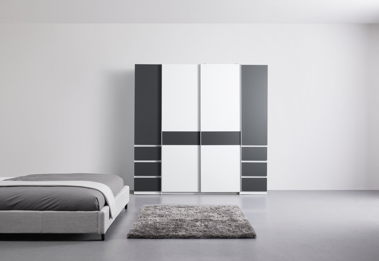 Moderne draai- en schuifdeurkast met vier deuren in een stijlvolle combinatie van wit en donkergrijs, hier afgebeeld in een minimalistische slaapkamer.
