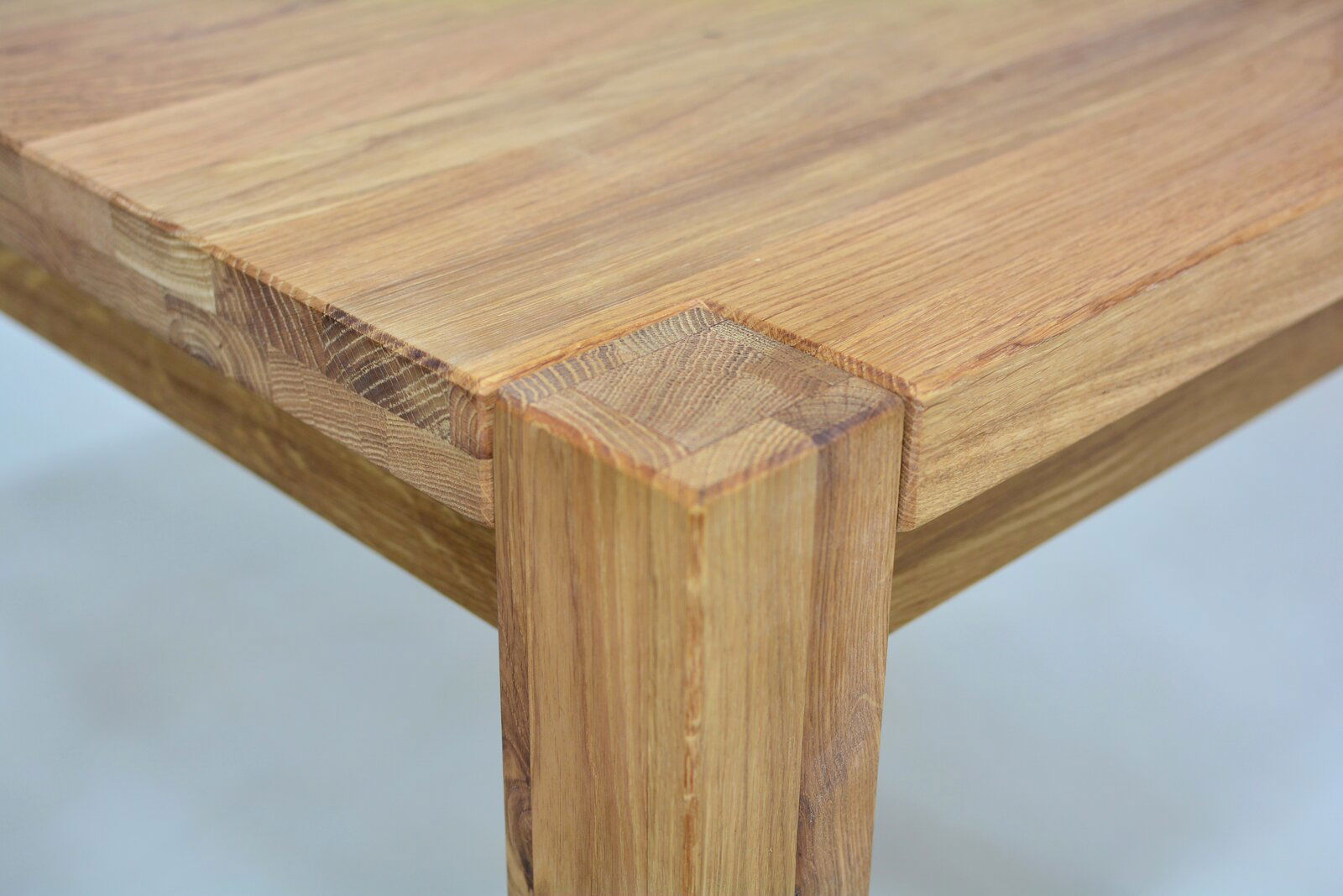 Nahaufnahme eines Esstisches aus Holz mit sichtbarer Maserung, Perspektive von der Ecke des Tisches.