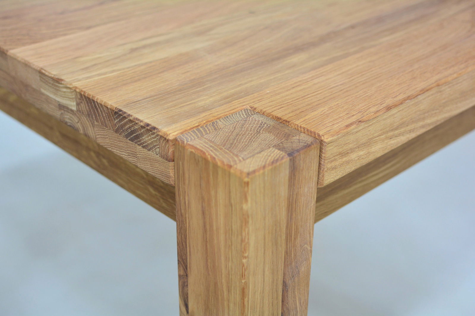 Nahaufnahme eines Esstisches aus Holz mit sichtbarer Maserung, Perspektive von der Ecke des Tisches.