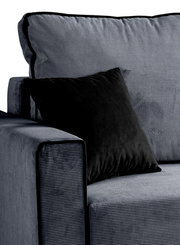 Nahaufnahme eines Schlafsofas in L-Form mit rechter Ausrichtung, grauer Stoff mit feiner Struktur und schwarzem Kissen, Perspektive von der Seite.