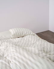 Bettwäsche 155x220cm mit dezentem Streifenmuster in einer Ecke eines Raumes, von oben fotografiert.