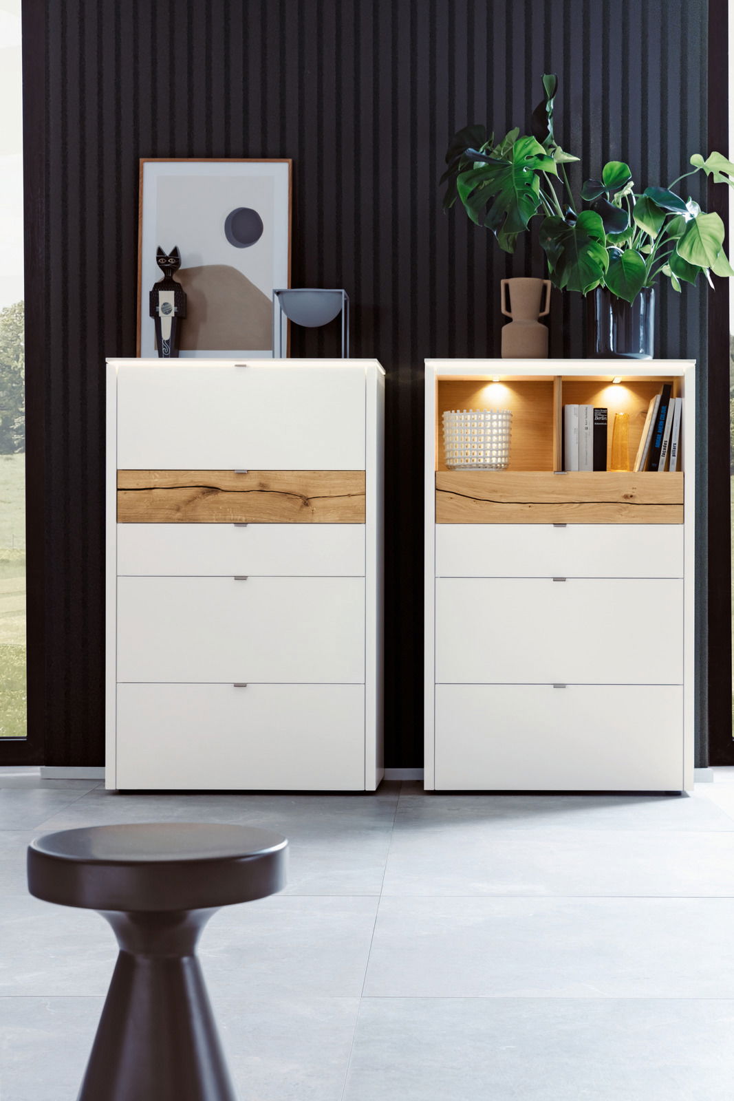 Zwei moderne Highboards in Weiß mit Holzelementen, dekoriert mit Pflanzen und Kunstobjekten, frontal betrachtet.