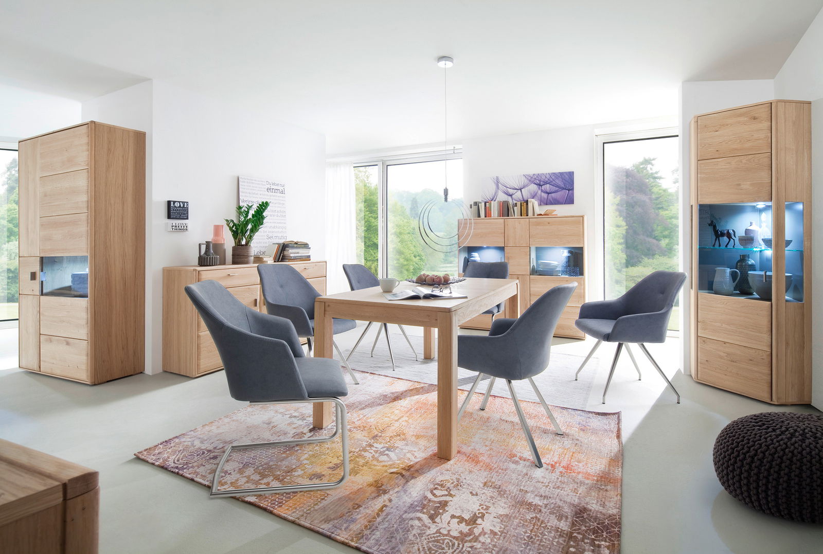 Moderne Esszimmermöbel aus Holz mit LED-beleuchteten Vitrinen, Sideboards und einem Esstisch, umgeben von grauen Stühlen. Perspektive: Frontalansicht des Esszimmers.