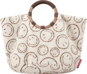 Frontansicht einer cremeweißen, flauschigen Shopper-/Tote-Bag mit braunem Smiley-Muster und rundem Ringgriff in Braun/Kupfer, seitlich mit kleinem roten reisenthel-Label.