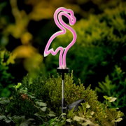 Solarbetriebene Stabbeleuchtung in Form eines rosa Flamingos, seitliche Perspektive, platziert in einem Garten.