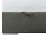 Nahaufnahme eines Boxbetts mit grauem Stoffbezug und silbernem Fuß, seitliche Perspektive