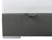 Nahaufnahme eines Boxbetts mit grauem Stoffbezug und silbernem Fuß, seitliche Perspektive