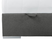 Nahaufnahme eines Boxbetts mit grauem Stoffbezug und silbernem Fuß, seitliche Perspektive