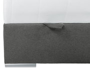 Nahaufnahme eines Boxbetts mit grauem Stoffbezug und silbernem Fuß, seitliche Perspektive
