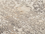 Nahaufnahme eines Designer Teppichs mit cremefarbenem und grauem Muster, aus seitlicher Perspektive aufgenommen.