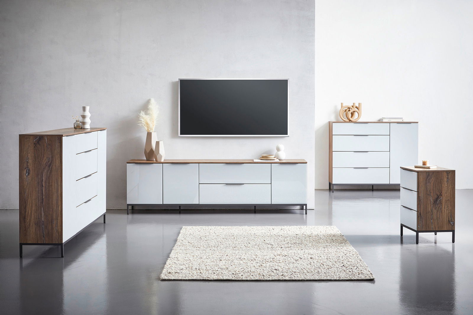 Moderne Wohnzimmermöbel in hellem Holz und Weiß, bestehend aus einem TV-Lowboard, einer Hochkommode und einer Nachtkonsole, frontal betrachtet.