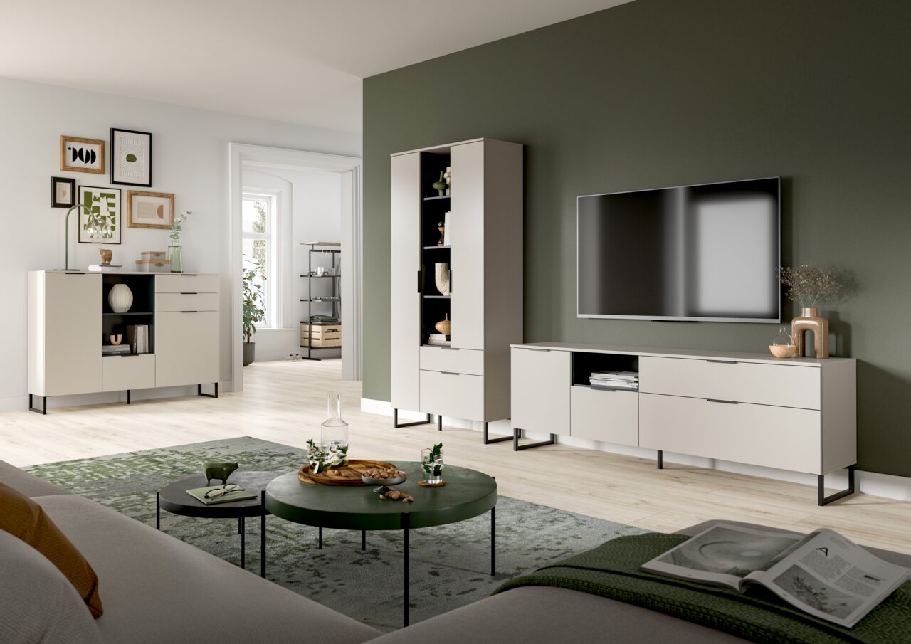Modernes Wohnzimmer mit hellen, minimalistischen TV-Möbeln (Lowboard, Vitrine und Sideboard) auf schwarzen Metallfüßen vor olivgrüner Akzentwand, TV an der Wand; Perspektive: Weitwinkelaufnahme aus leicht erhöhter, frontaler Blickrichtung.