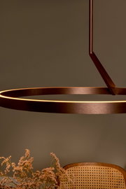 Moderne, ringförmige LED-Pendelleuchte in Bronze/Kupferoptik mit warmweiß leuchtendem Lichtband, schräg von unten im Detail fotografiert