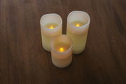 Drei Outdoor-Kerzen in verschiedenen Größen auf einem Holztisch, von oben betrachtet, mit warmem LED-Licht.