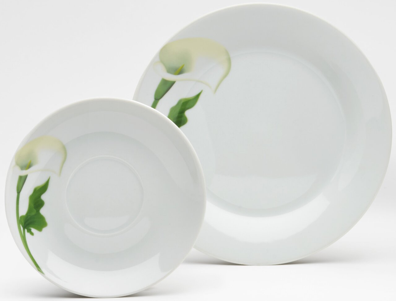 Zwei weiße Porzellan-Teller mit Calla-Blumenmotiv in Grün und Creme, frontal leicht von oben fotografiert, ein kleiner Teller vor einem größeren auf hellem Hintergrund.