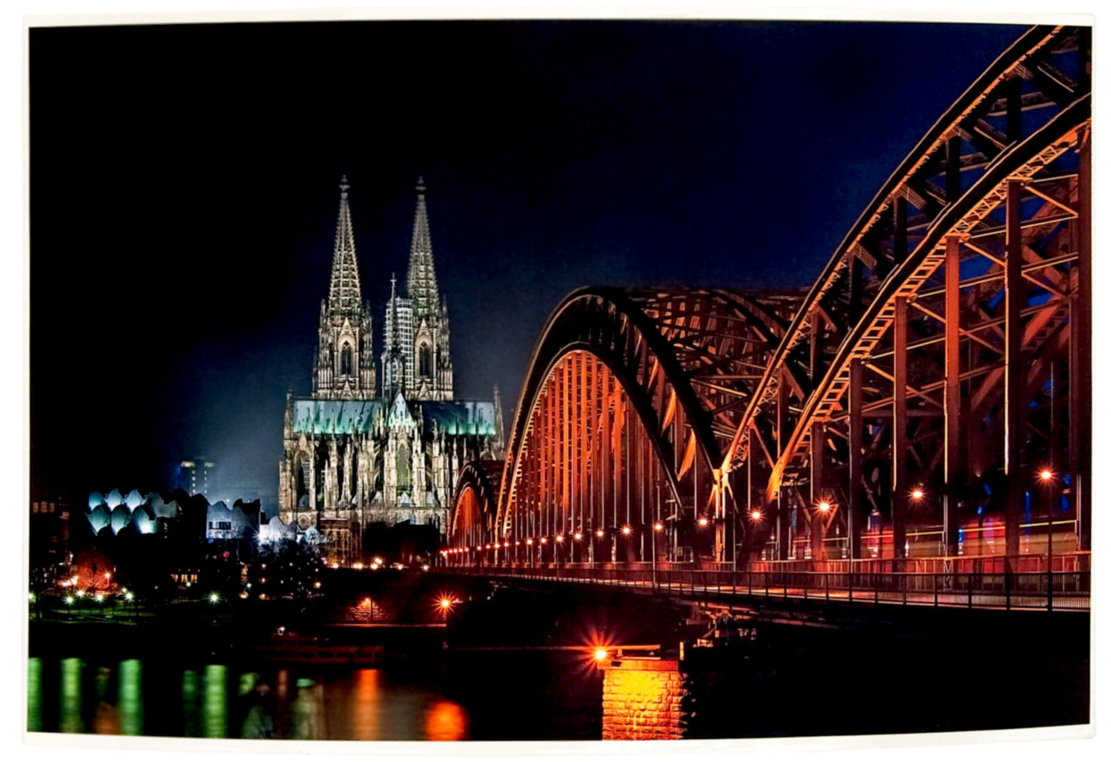 Nachtaufnahme des Kölner Doms und der Hohenzollernbrücke, seitliche Perspektive