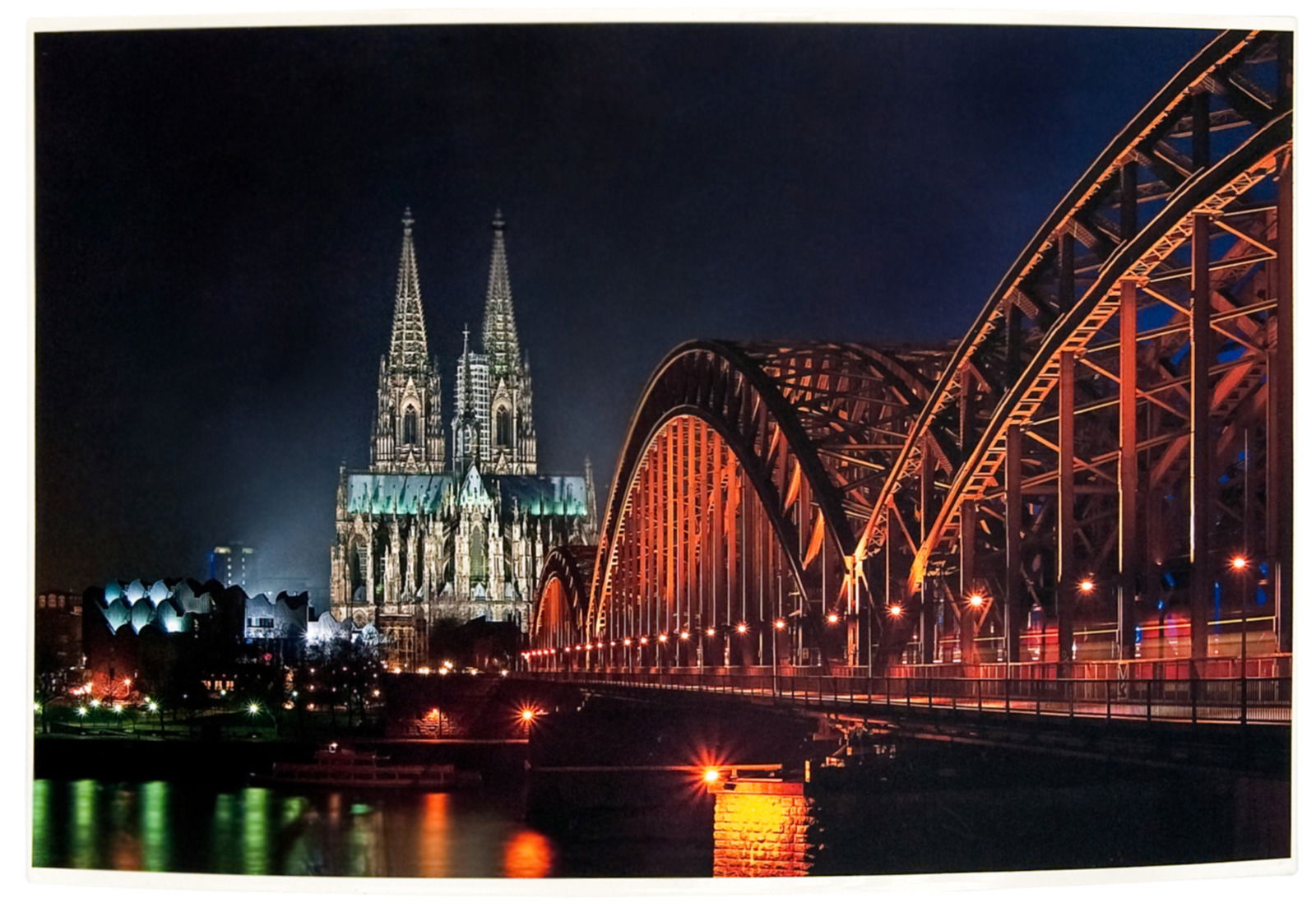 Nachtaufnahme des Kölner Doms und der Hohenzollernbrücke, seitliche Perspektive