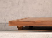 Seitliche Ansicht einer Schneide- und Abdeckplatte aus Holz auf einer Küchenoberfläche.