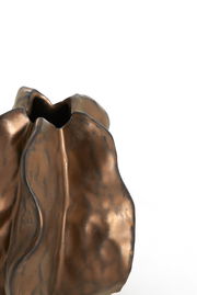 Nahaufnahme einer dekorativen Vase mit unregelmäßiger, welliger Oberfläche in bronzefarbener Optik, seitliche Perspektive.