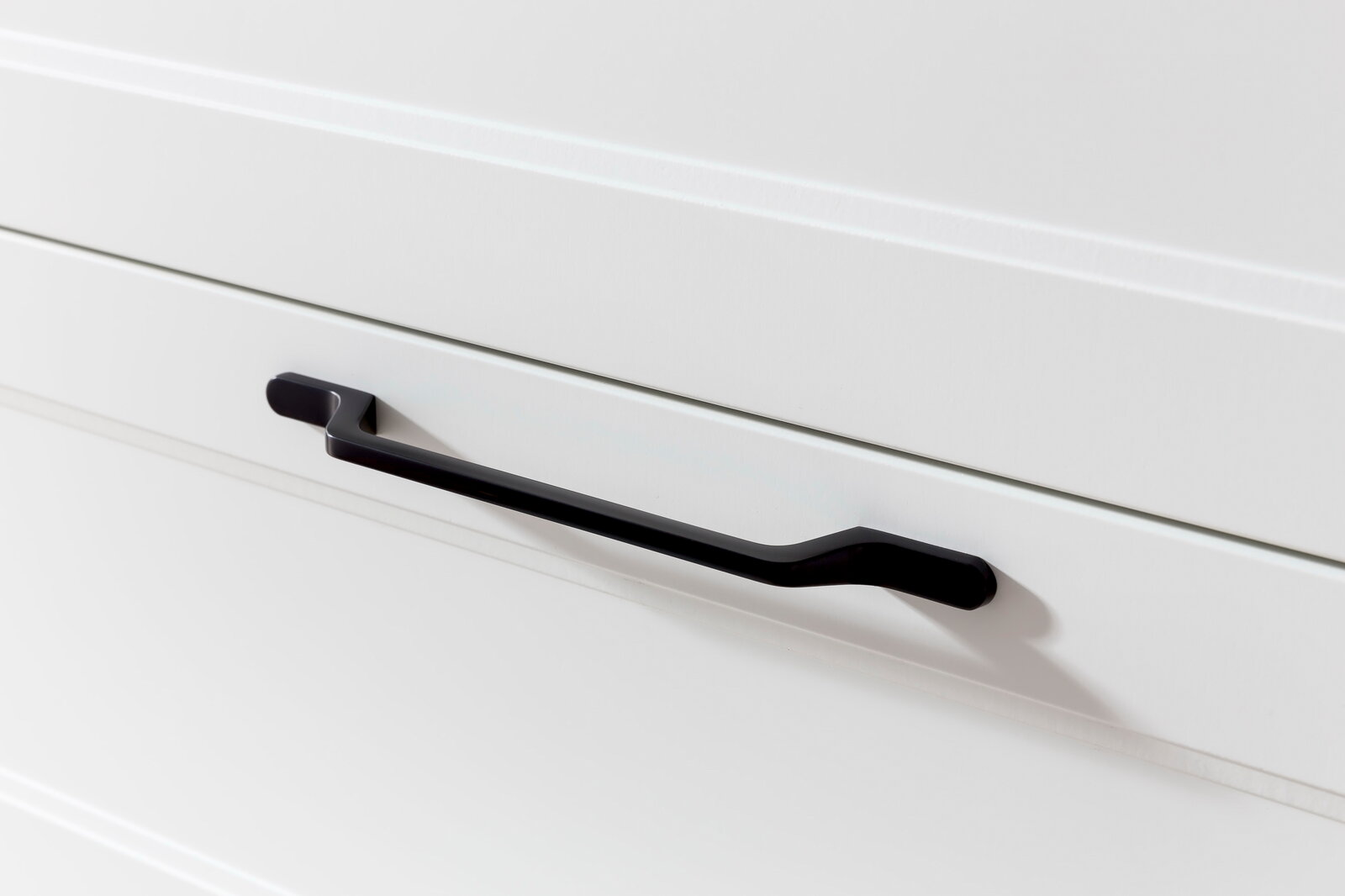 Nahaufnahme eines schwarzen Griffs an einer weißen Schublade, seitliche Perspektive