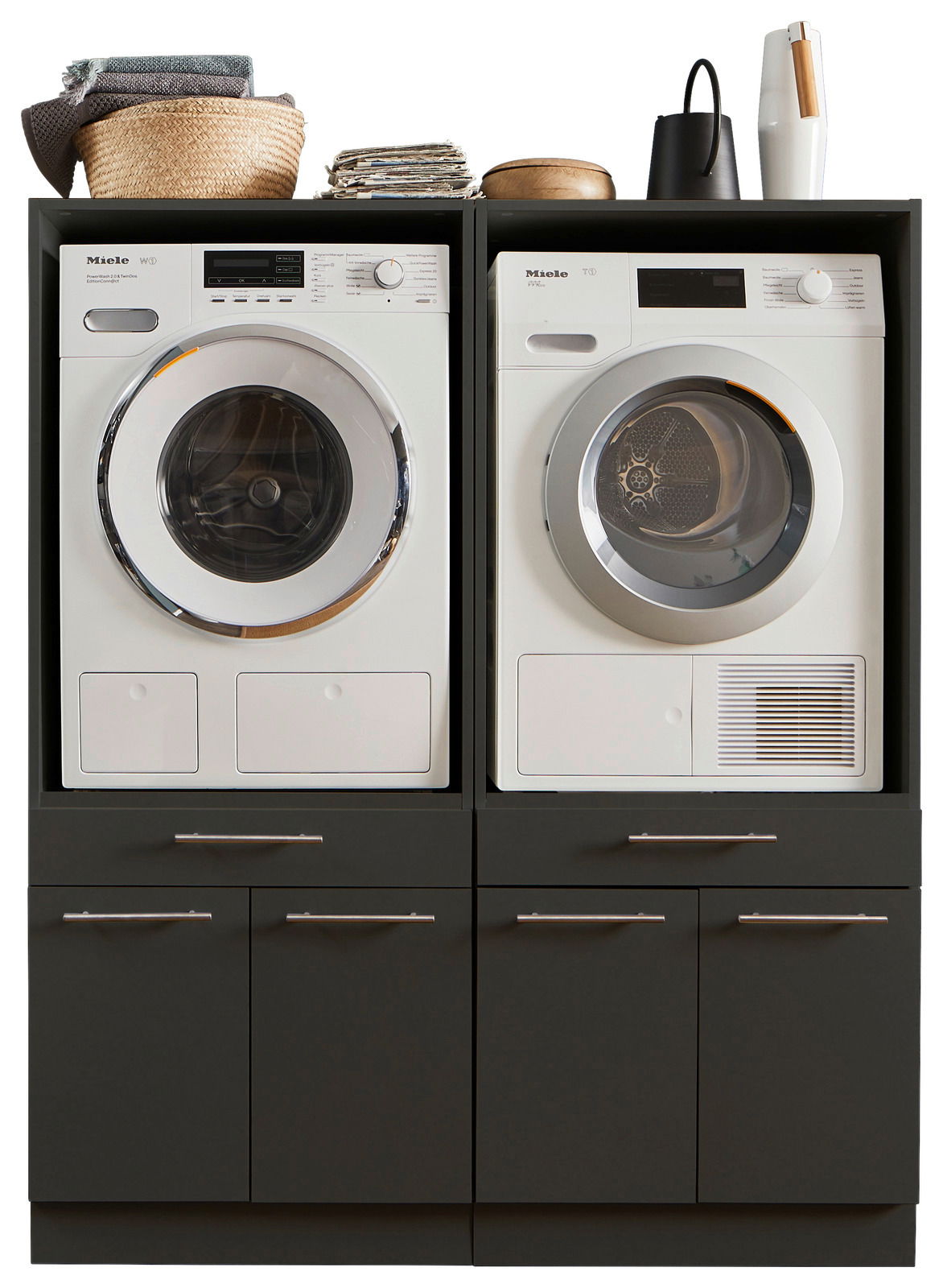 XORA Hauswirtschaftsraum-Kombi PRIMUS Frontansicht einer Hauswirtschaftsraum-Kombination mit Waschmaschine und Trockner, umgeben von dunklen Schränken und dekorativen Elementen oben.