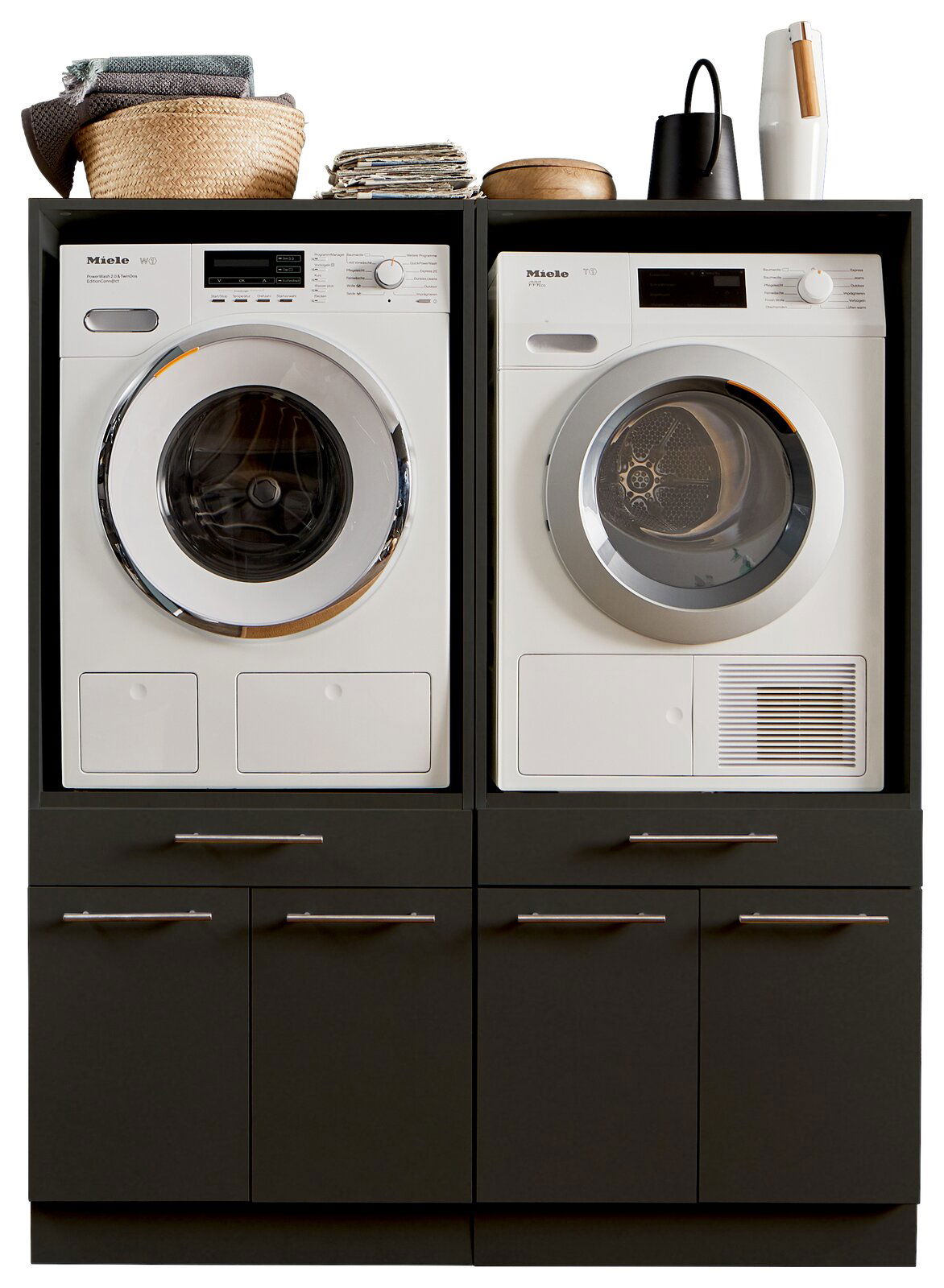 XORA Hauswirtschaftsraum-Kombi PRIMUS Frontansicht einer Hauswirtschaftsraum-Kombination mit Waschmaschine und Trockner, umgeben von dunklen Schränken und dekorativen Elementen oben.