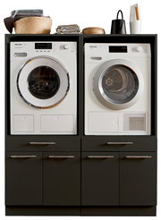 Frontansicht einer Hauswirtschaftsraum-Kombination mit Waschmaschine und Trockner, umgeben von dunklen Schränken und dekorativen Elementen oben.
