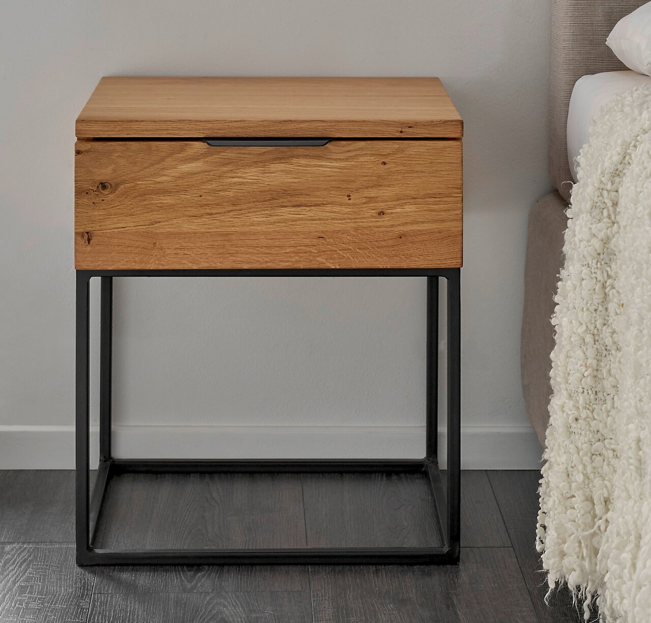 Moderne Nachtkommode aus Holz mit Metallgestell, frontal fotografiert neben einem Bett.