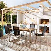 Moderner Gartentisch mit Holzplatte und Metallgestell, umgeben von sechs stilvollen Stühlen auf einer Terrasse mit Blick auf einen Pool und eine Außenküche.