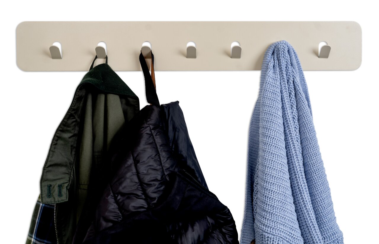 Garderobenleiste mit fünf Haken, an denen verschiedene Kleidungsstücke hängen, aus frontaler Perspektive.
