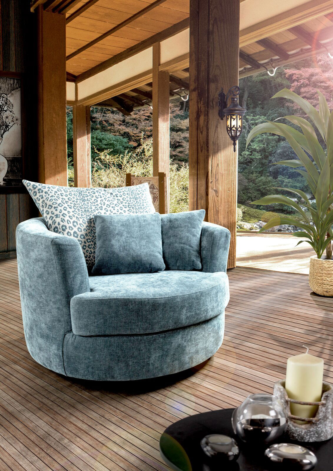 Z2 Sessel LENI Gemütlicher blauer Sessel mit runden Formen und Kissen, auf einer Terrasse mit Blick auf einen Garten, aus seitlicher Perspektive.