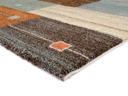 Nahaufnahme eines Frisé-Teppichs mit geometrischem Muster in Braun-, Beige- und Blautönen, perspektivisch von der Seite aufgenommen.