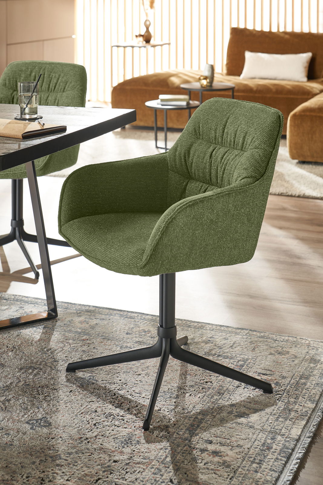 Grüner Armlehnstuhl mit schwarzem Metallgestell, seitliche Perspektive