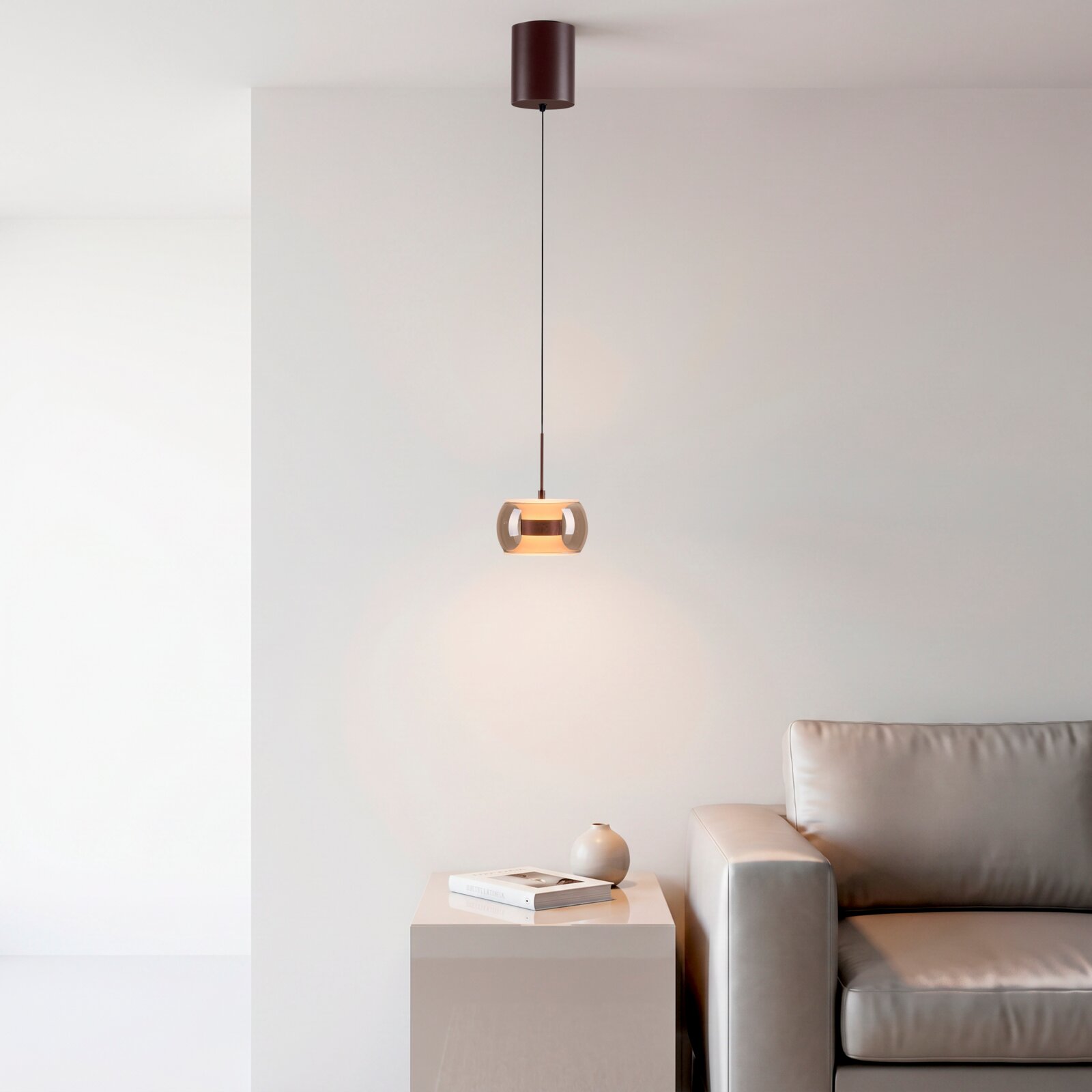 Paul Neuhaus LED-Hängeleuchte FUMEA Moderne Pendelleuchte mit zylindrischem Baldachin und getöntem Glas-Schirm in warmem Licht, hängend über einem Beistelltisch neben grauem Sofa; Frontansicht leicht von unten im Wohnraum.